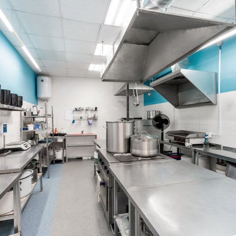 Modern restaurant kitchen with stainless steel kitchenware and equipment. Cooking with preparation tables, pans, pots, stoves.