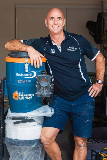 Epoxy Flooring Co team member leaning on a floor grinding dust extractor in the workshop