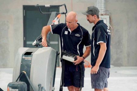 Two Epoxy Flooring Co installers setting up a floor grinder