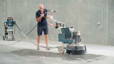Installer grinding a concrete floor before industrial epoxy flooring