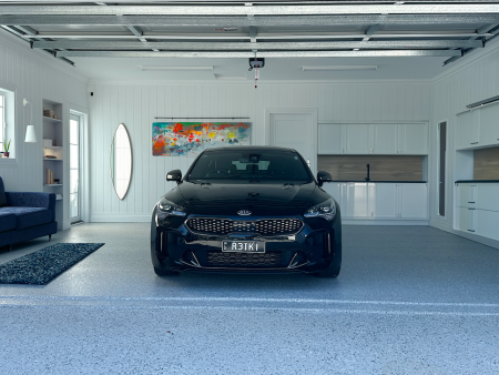 Hastings flake epoxy floor in a garage with a black Kia Stinger